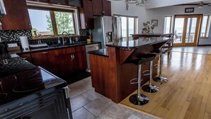 Uma cozinha moderna com armários de madeira escura, uma geladeira de aço inoxidável e uma ilha grande com banquetas.
