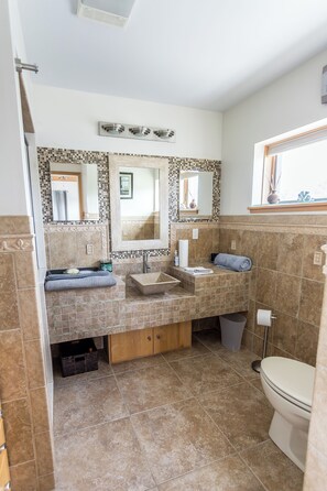 Een badkamer met twee wastafels, een toilet en een raam.