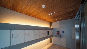 Un couloir moderne avec des casiers, un système d’alarme incendie et un ascenseur en verre.