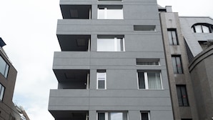 Un immeuble moderne à plusieurs étages, doté d’une façade plate, de nombreux balcons et d’une entrée centrale.