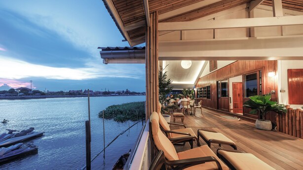A waterfront balcony with seating, a view of the river, and a restaurant area with wooden architecture. - Private Villa (Tambon Ko Kret)