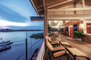 Un balcón sobre el río con asientos, vistas al río y una zona de restaurante con arquitectura de madera.