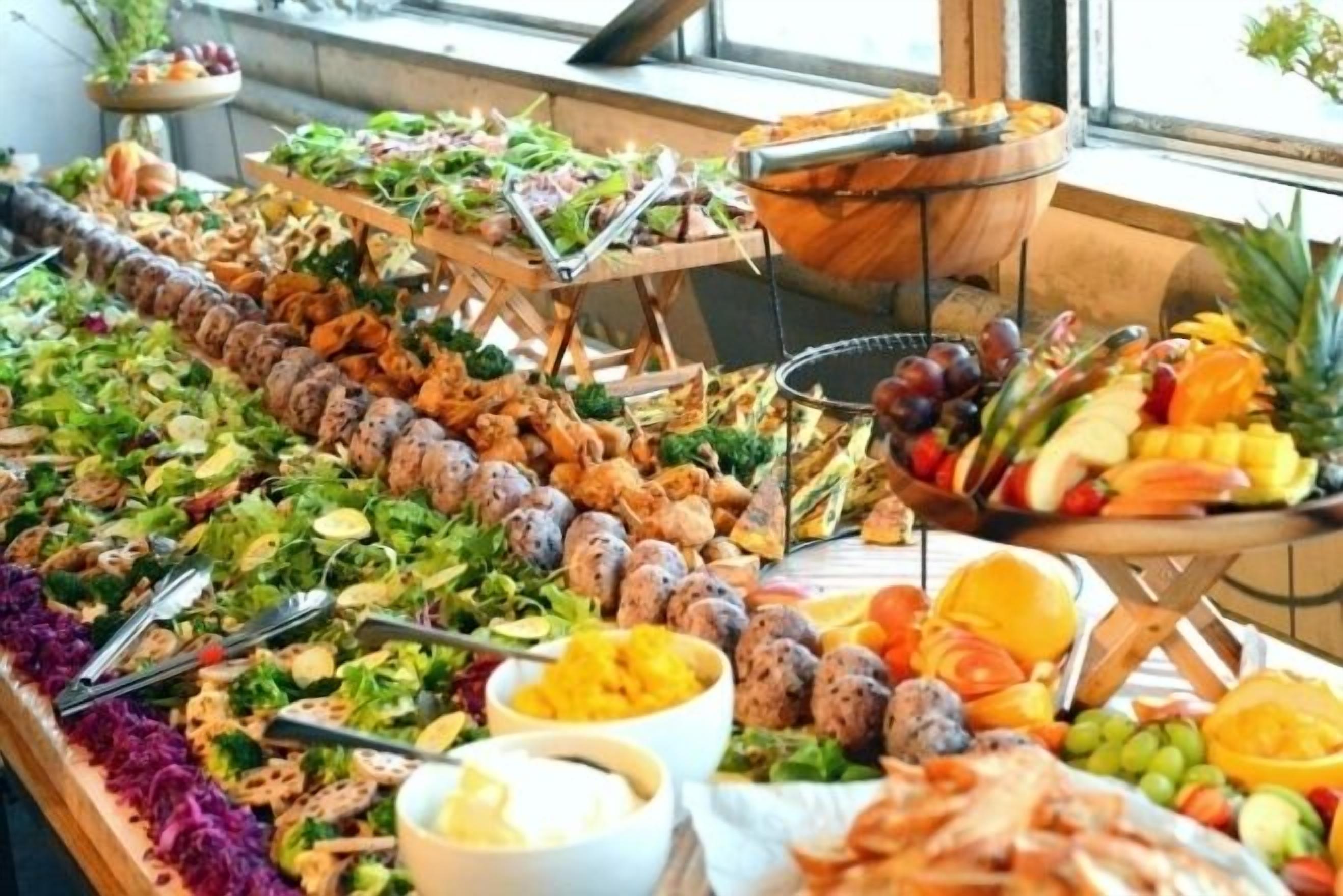 A buffet with various food items including salads, meats, and fruits.