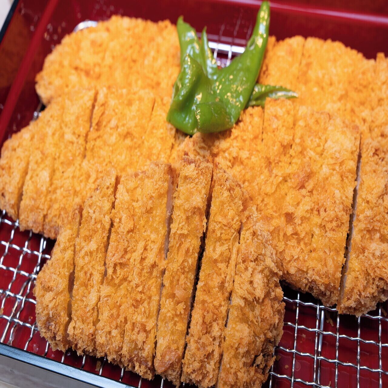 Un plat amb aliments refrits i empanats, probablement un plat japonès, i un guarniment de chili verd.