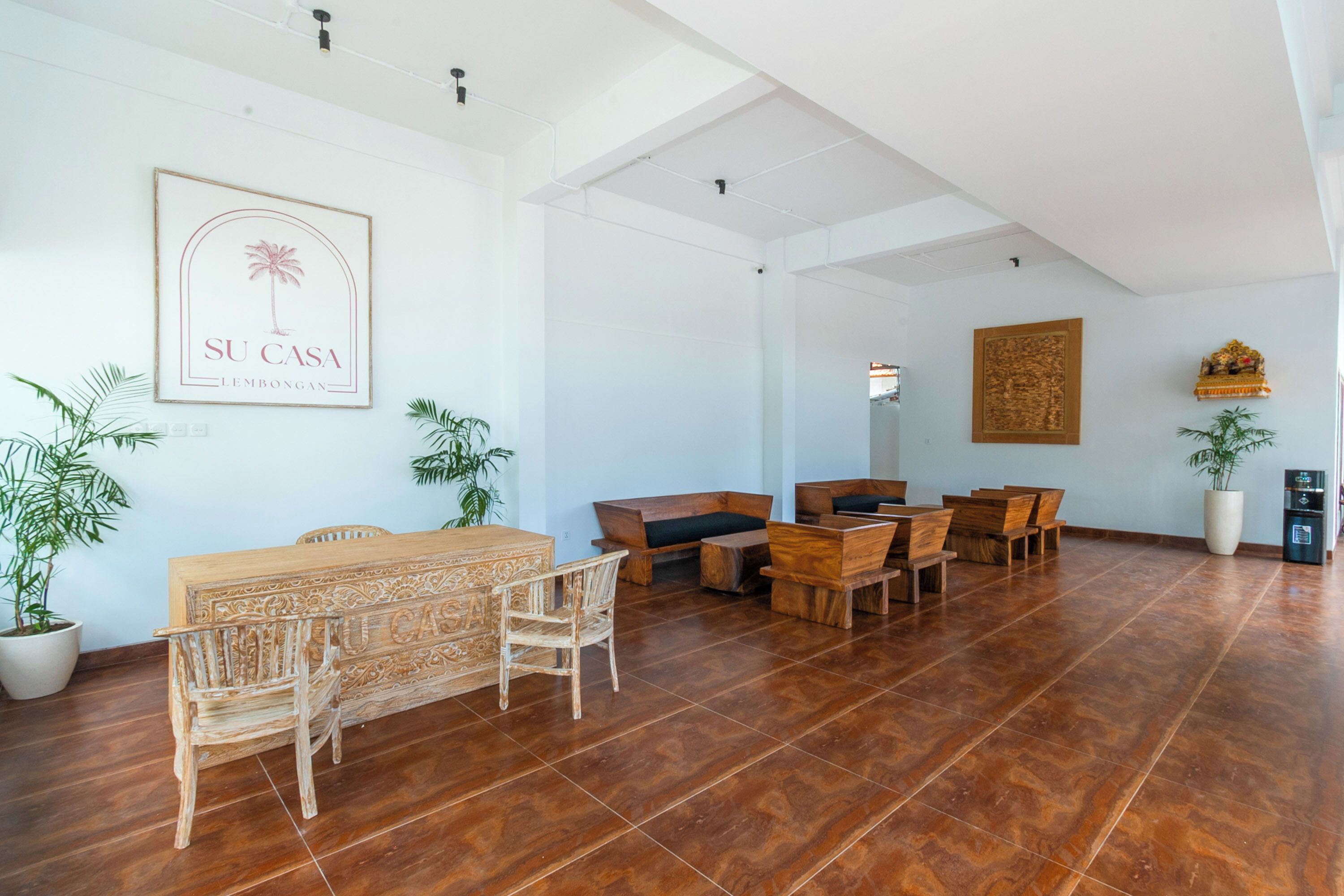 A spacious room with a wooden dining table and chairs, a sofa, and a large potted plant.