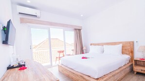Una habitación de hotel con una cama y un escritorio de madera, un televisor y una puerta corredera de vidrio al exterior.