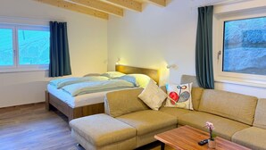 A modern room with a bed, a sofa, a small table, and a window with curtains.