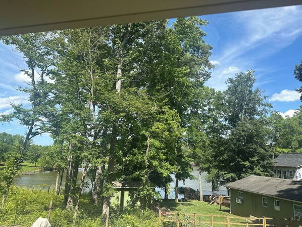 A view of a lake surrounded by trees and a house with a dock.