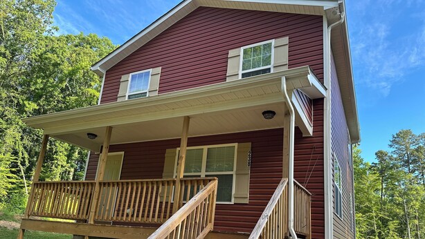 A two-story house with a wooden deck and a staircase leading to the front porch. - The Red Nest At High Rock Lake - Fire Pit, Front Porch Deck, Sunset & Lake Views (Lexington)
