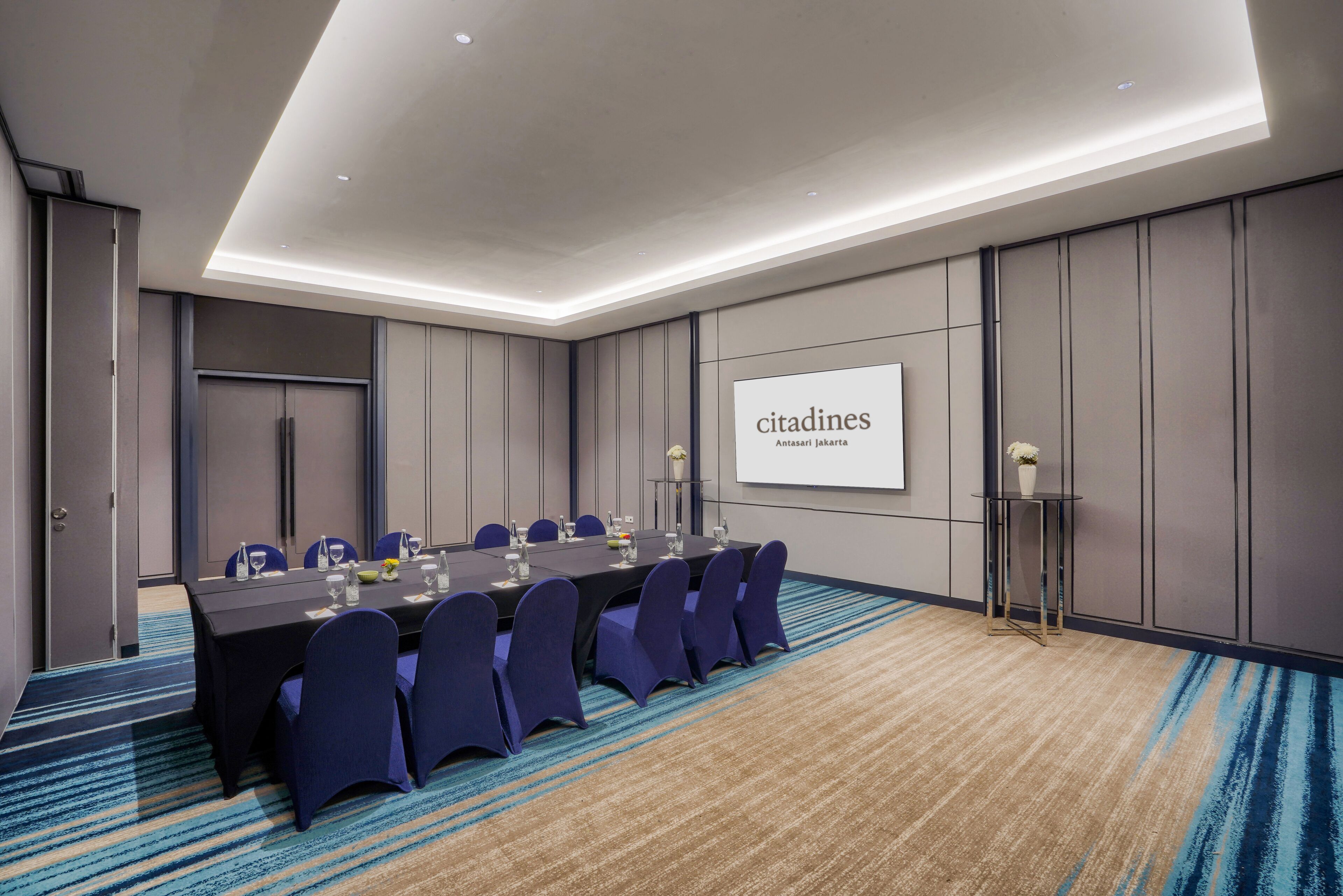 Un salón de conferencias con una larga mesa, sillas y una pantalla de proyector mostrando 'citasdines'.