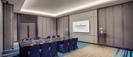 A conference room with a long table, chairs, and a projector screen displaying 'citasdines'.