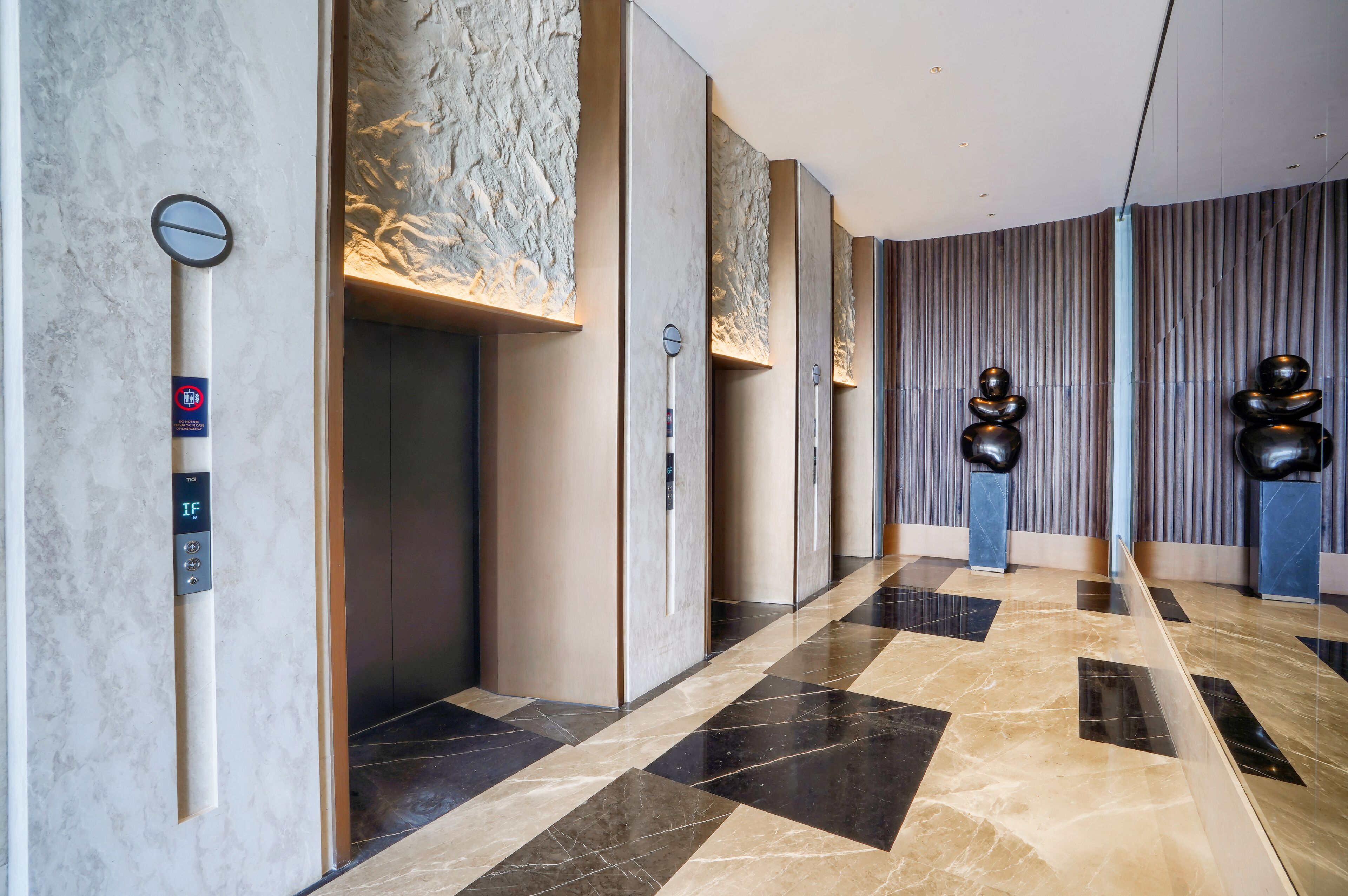 A modern elevator with a digital display, a marble wall with a textured pattern, and a floor with a geometric tile design.