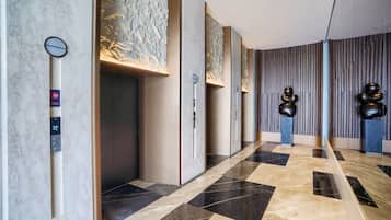 A modern elevator with a digital display, a marble wall with a textured pattern, and a floor with a geometric tile design.