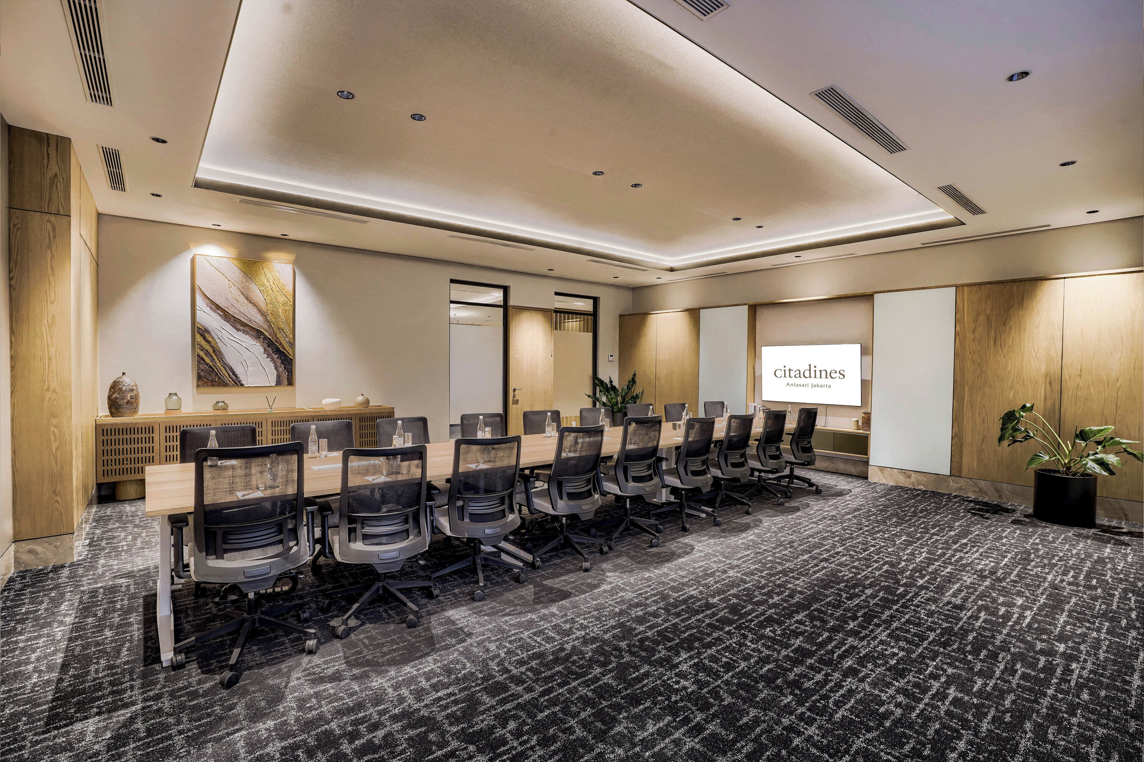 A conference room with a long table, chairs, and a projector screen.