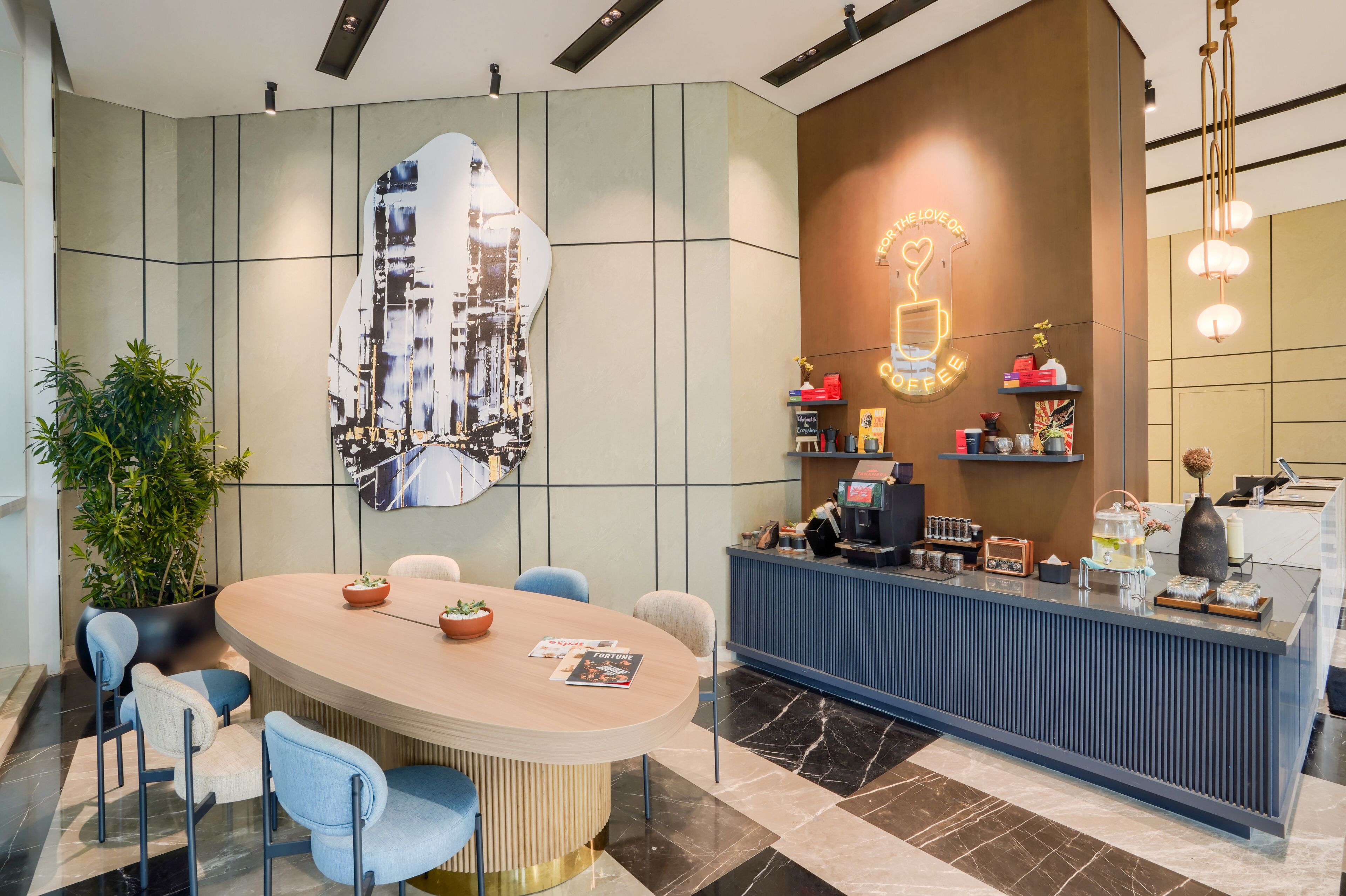 Een moderne bar met een koffiemachine, planken vol koffieproducten en een neonreclame.