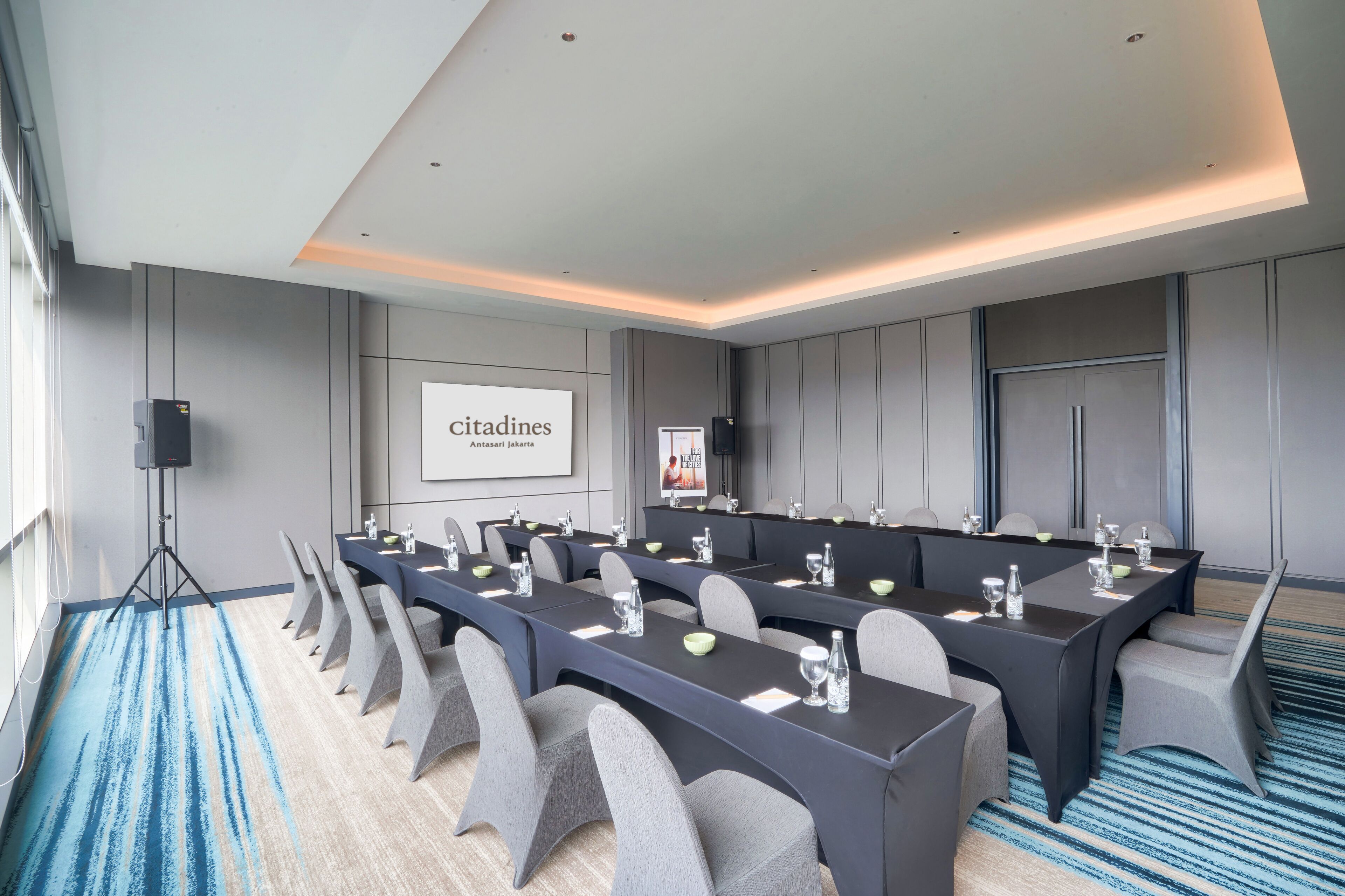 Un salón de conferencias con una larga mesa, varias sillas y una pantalla de proyector que muestra 'CITADINES'.