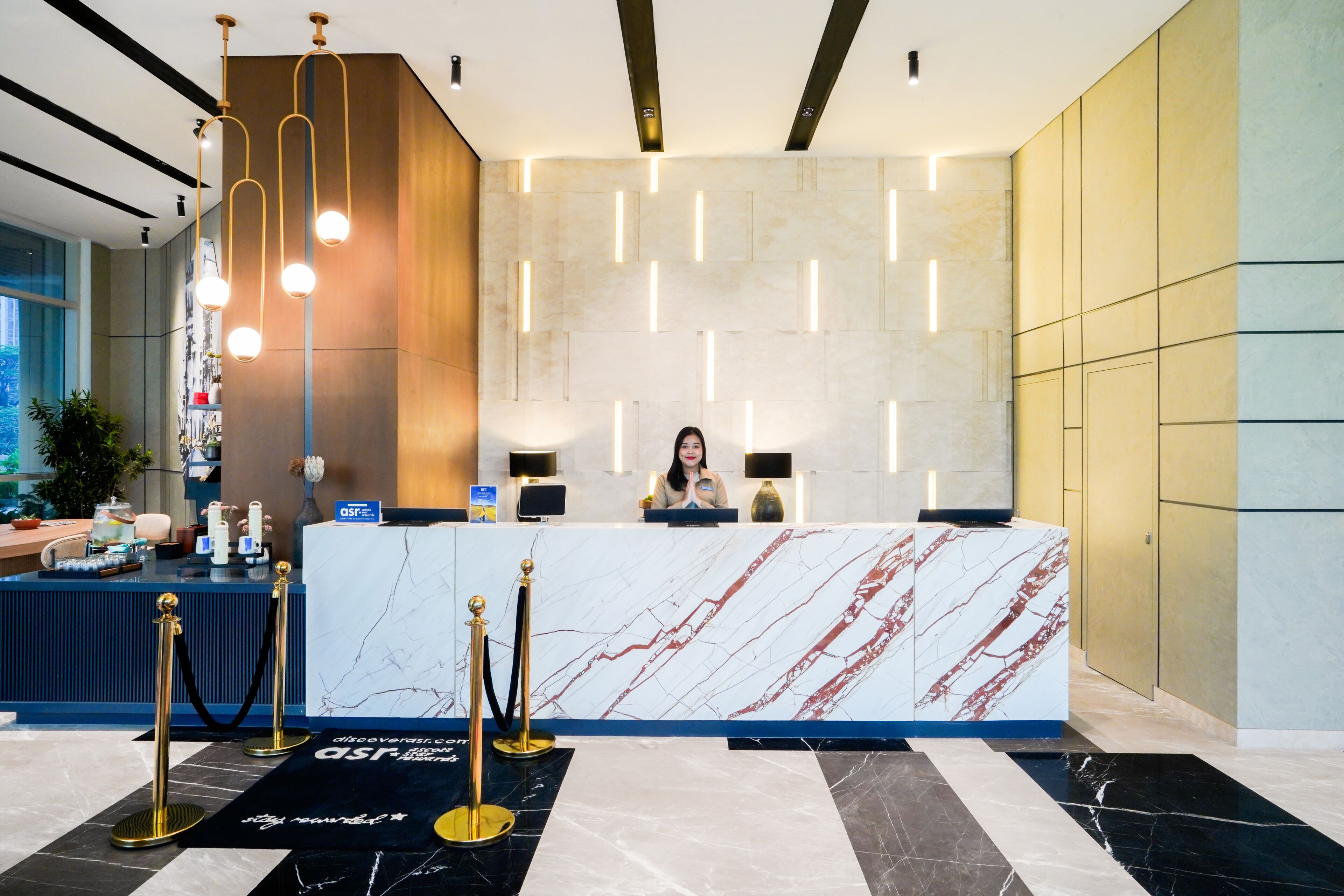 A reception desk with a marble top, a receptionist, and a modern interior design.