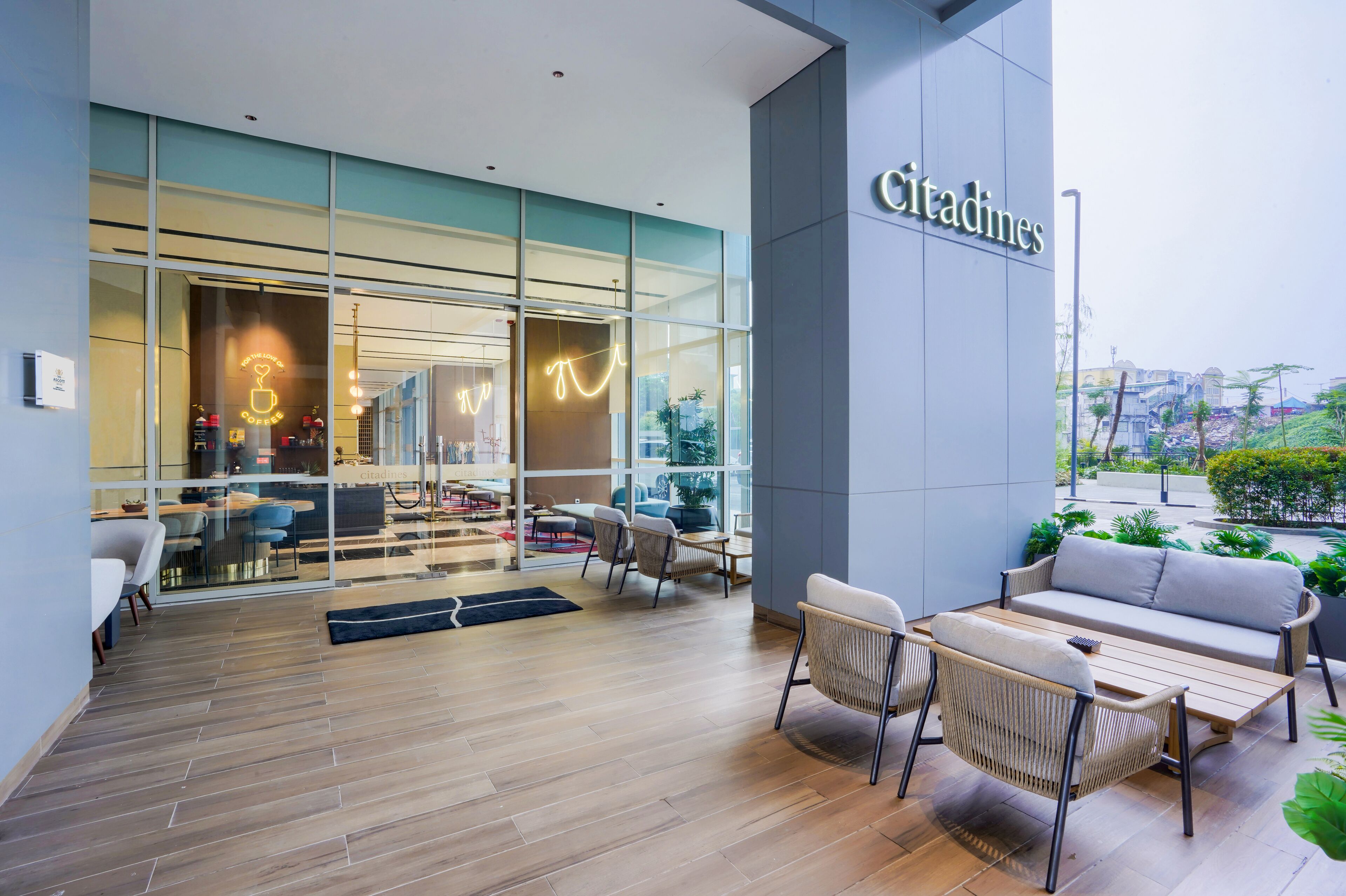 A modern cafe with a glass facade, outdoor seating, and a sign reading 'Citadines'.
