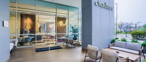 A modern cafe with a glass facade, outdoor seating, and a sign reading 'Citadines'.