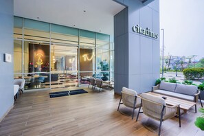 Un café moderne avec une façade en verre, des tables en terrasse et une enseigne indiquant « Citadines ».