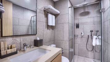 Un baño moderno con un lavamanos grande, un inodoro, una cabina de ducha de vidrio y un perchero con toallas dobladas.