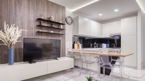 Une cuisine moderne avec des armoires blanches, un mur en bois et un téléviseur encastré.