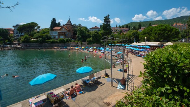 Un hôtel situé au bord de l’eau, doté d’une piscine, de chaises longues et de parasols.