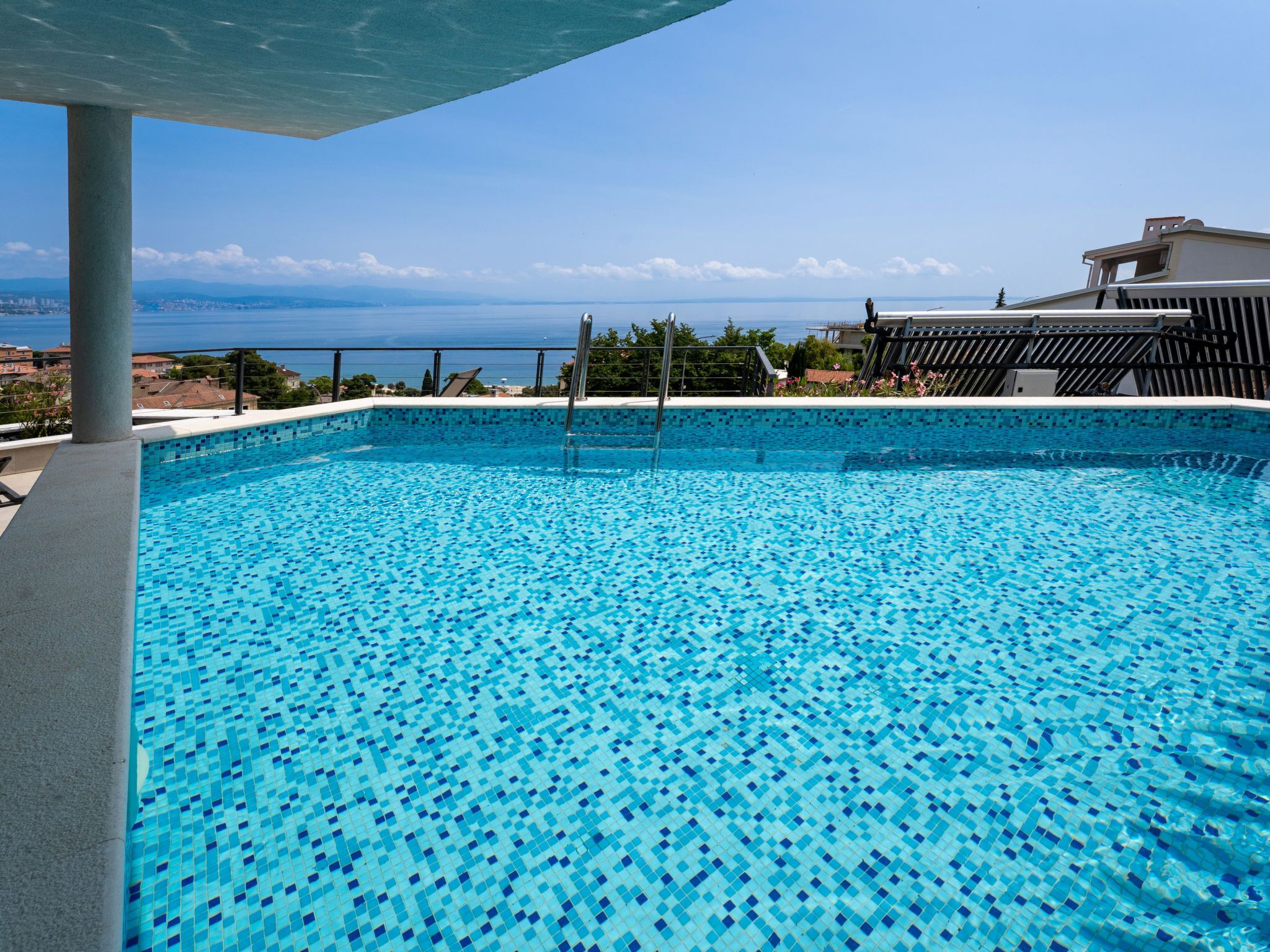 Une piscine avec un sol carrelé et vue sur la mer.