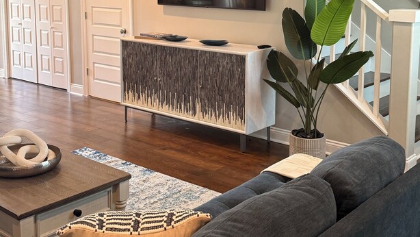 Un salón moderno con un sofá gris, una mesa de centro de madera, un cuenco decorativo y una planta en maceta.