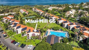 Vista aérea de un complejo turístico con varias edificaciones, una piscina y paneles solares en los tejados.