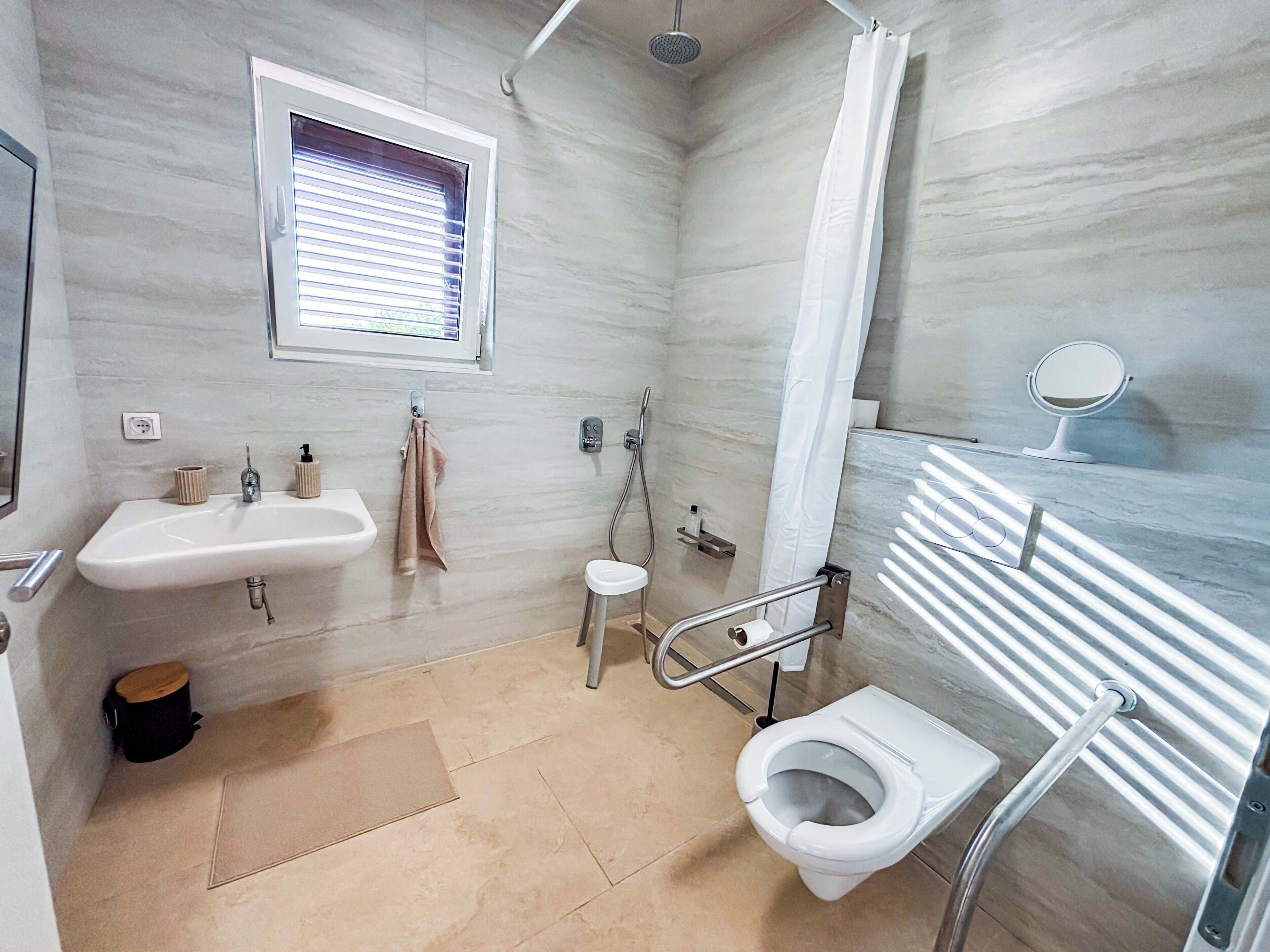 Et stilfuldt badeværelse med vask, toilet, brusebad og et vindue.