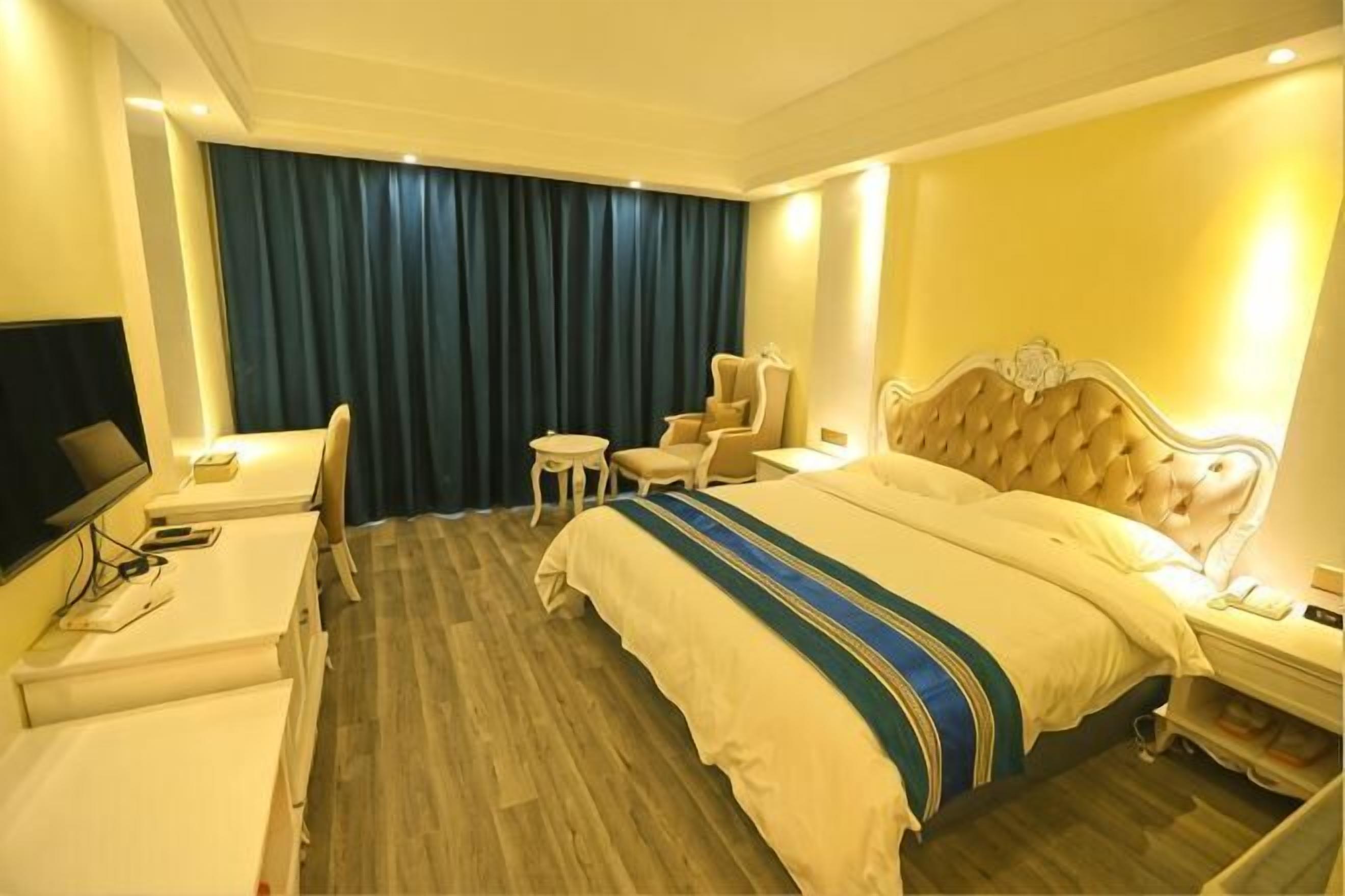 Une chambre d’hôtel comprenant un lit, un bureau, une chaise, une petite table et un téléviseur.