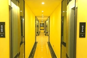 Pasillo de hotel con paredes espejadas y puertas numeradas, que conduce a un punto central.