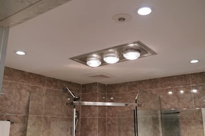 Un bagno moderno con box doccia in vetro, faretti a soffitto e piastrelle in marmo.