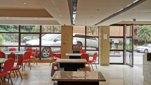 Ravintolassa on sisätilat, suuret ikkunat ja näköala ulkona parkissa oleviin autoihin.