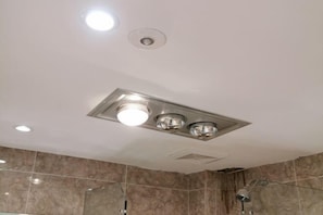 Un bagno moderno con doccia, faretti a soffitto e pareti in marmo.