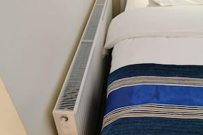 Un letto con un cuscino bianco e una coperta blu a righe orizzontali.