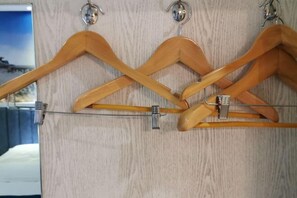 A wooden coat rack with multiple hooks against a textured wall. - Qiliping YaDuoVacationHotel (Hongya)