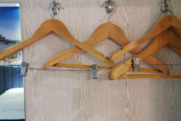 Un appendiabiti in legno con diversi ganci appoggiato su una parete strutturata.
