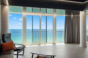 A spacious room with a large sliding glass door leading to a balcony with a view of the ocean.