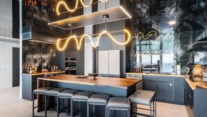 Een moderne keuken met een centraal eiland, barstoelen en hanglampen.