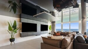 Een moderne woonkamer met een grote hoekbank, een flatscreen televisie en een groot raam met uitzicht op de oceaan.