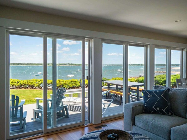 Una habitación con grandes puertas corredizas de vidrio que dan a una terraza exterior con vistas al agua y barcos.