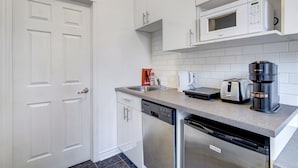 A modern kitchen with white cabinets, a dishwasher, a coffee maker, and a toaster.