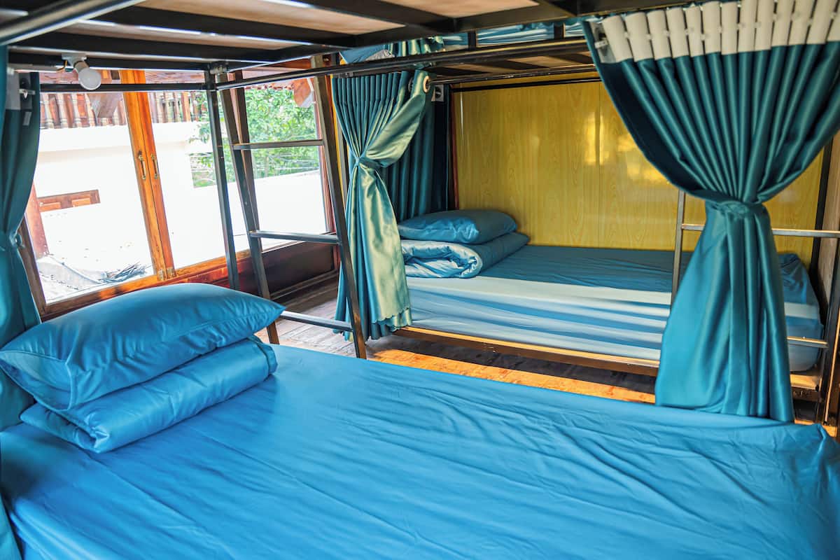 Un compartimento de tren con dos camas, cada una con ropa de cama y cortinas azules.