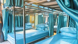 A train carriage with bunk beds, curtains, and metal railings. - Golden Mountain Hostel  (Ninh Binh)