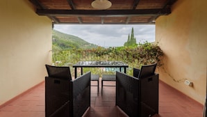 Une terrasse couverte, meublée de mobilier en osier, avec vue sur un vignoble.
