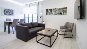 A modern living room with a sofa, armchair, coffee table, and artwork on the walls.