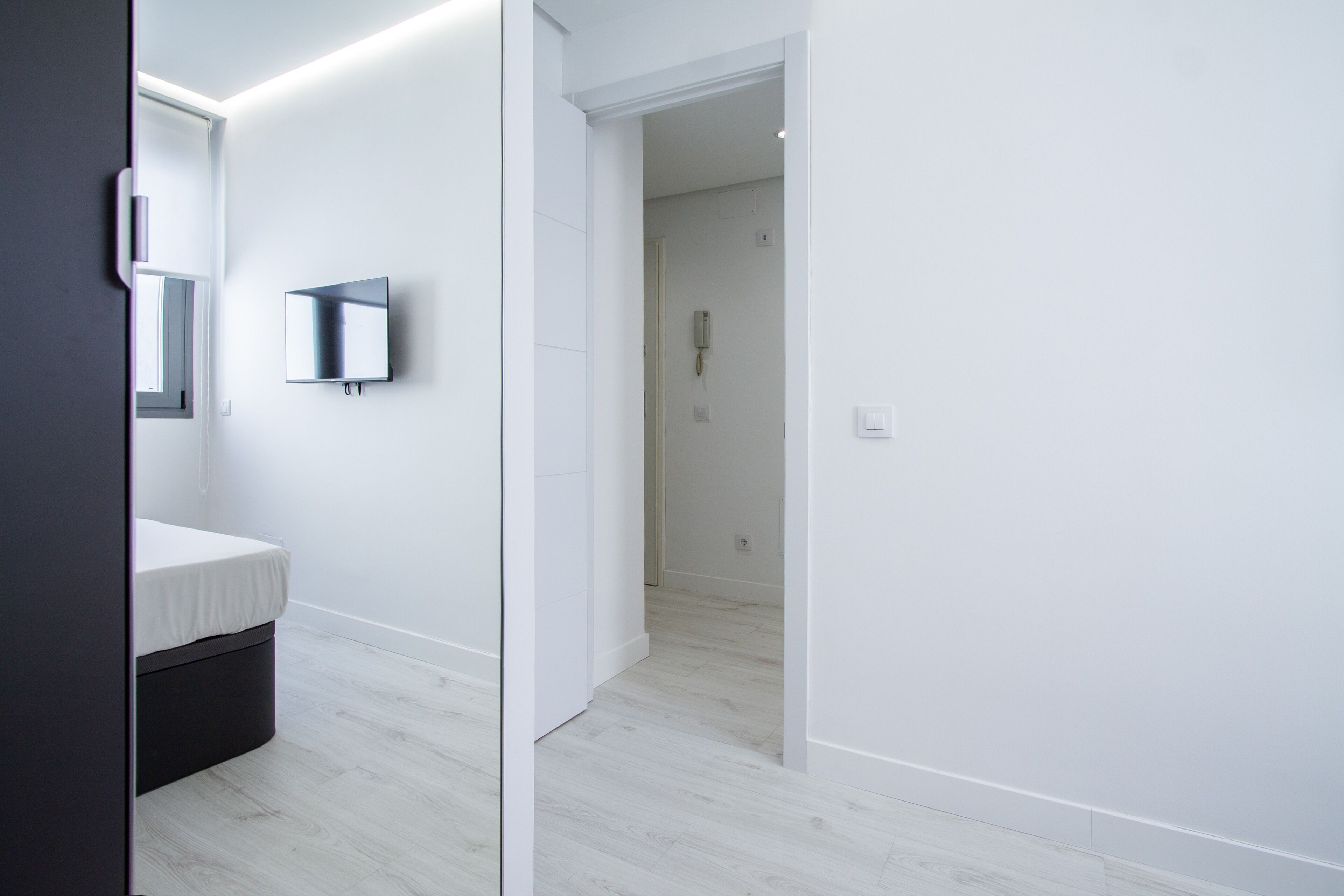 Une salle de bain moderne avec un lavabo blanc, un miroir et un téléviseur fixé au mur.