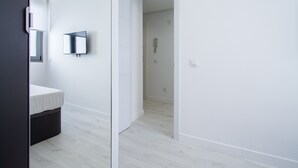 A modern bathroom with a white sink, mirror, and a wall-mounted TV.